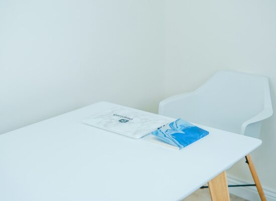 Bright, modern, and welcoming therapist's office with a laptop open on a clean desk next to a green plant, signifying the ...